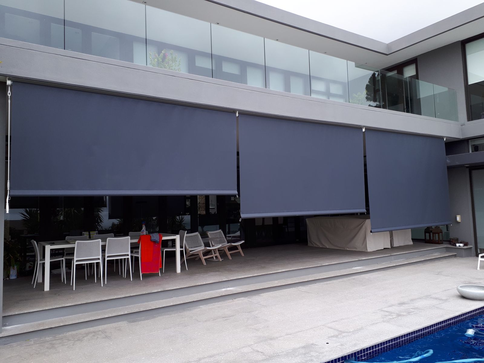Full-width drop blinds on a pool patio